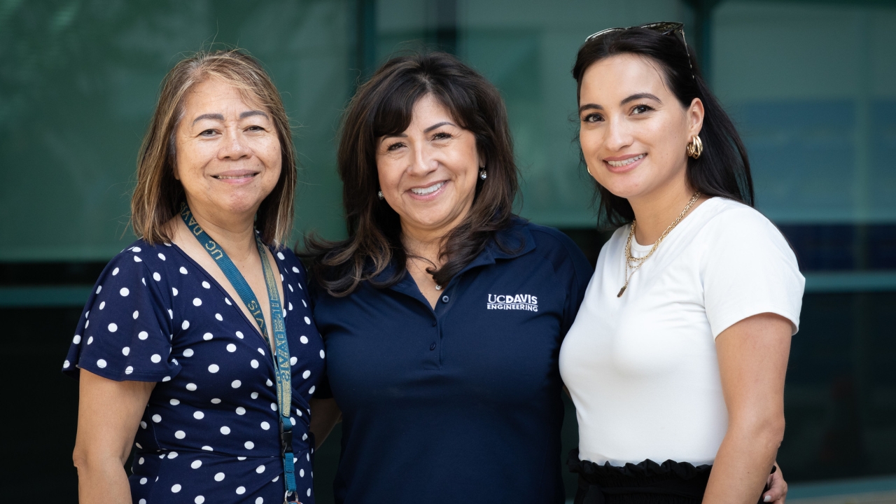 Three women stand together outside for a group photo