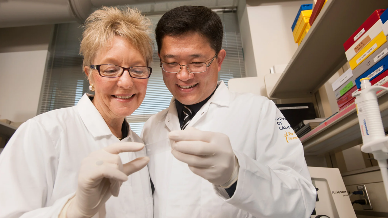 Farmer and Wang in white coats in a lab