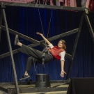 A girl hanging from thin string attached to a beam